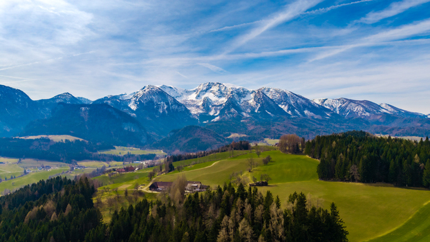 Aerial view of the valley s verdant patchwork quilt stretching towards the snow capped mountains under a vast azure sky Windischgarsten Upper Austria Austria. Aerial view of the valley s verdant patchwork quilt stretching towards the snow capped mountains under a vast azure sky Windischgarsten Upper Austria Austria.