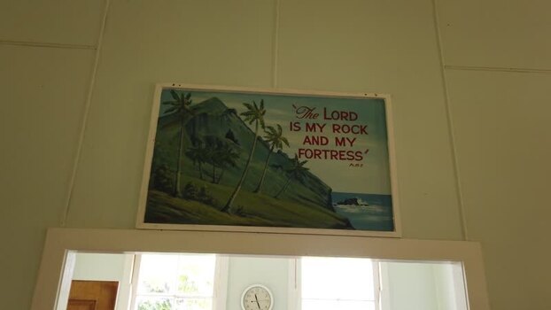 Aerial view of a room with a clock and a framed picture of a mountain with palm trees location omitted location omitted.