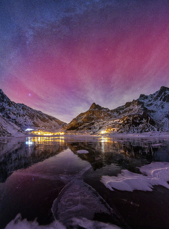 View of the vibrant pink aurora borealis reflecting on a frozen mountain lake surrounded by snow covered peaks at night in Madesimo Lombardy Italy. View of the vibrant pink aurora borealis reflecting on a frozen mountain lake surrounded by snow covered peaks at night in Madesimo Lombardy Italy.