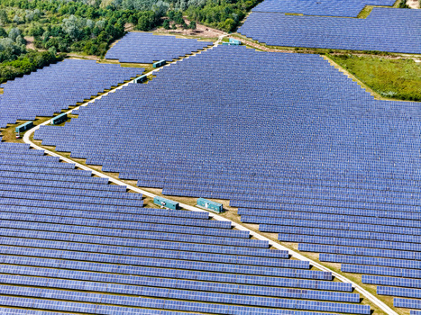 Aerial view of a large solar panel farm with rows of blue photovoltaic modules and green containers surrounded by lush forest in Torrazza Piemonte Piemonte Italy. Aerial view of a large solar panel farm with rows of blue photovoltaic modules and green containers surrounded by lush forest in Torrazza Piemonte Piemonte Italy.