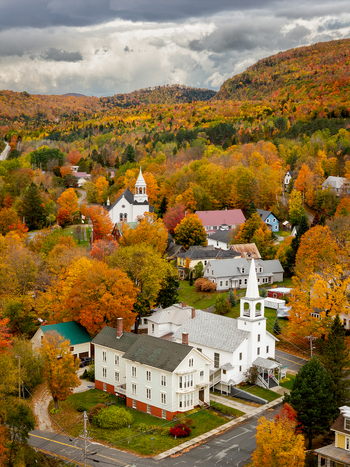 Aerial view of fall foliage in Island Pond village featuring historic white churches colorful autumn trees and rolling hills in Brighton Vermont USA. Aerial view of fall foliage in Island Pond village featuring historic white churches colorful autumn trees and rolling hills in Brighton Vermont USA.