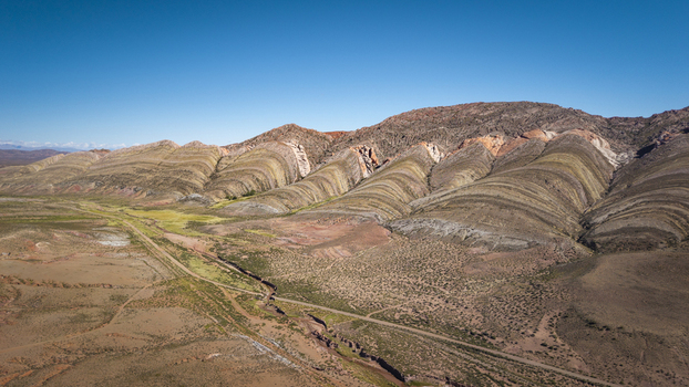 Aerial view of Gigantes Dormidos mountain range featuring colorful sedimentary rock layers and rugged desert terrain in Tres Cruces Jujuy Province Argentina. Aerial view of Gigantes Dormidos mountain range featuring colorful sedimentary rock layers and rugged desert terrain in Tres Cruces Jujuy Province Argentina.