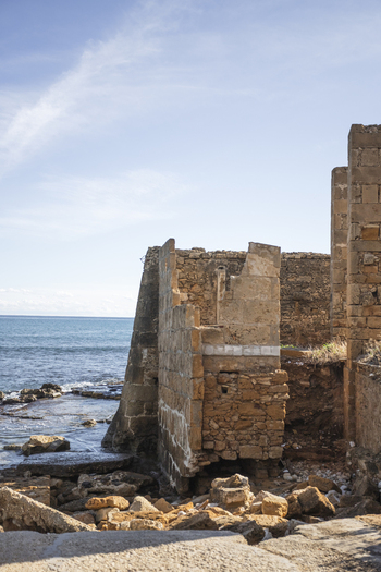 View of the historic stone ruins of the Tonnara di Avola overlooking the Mediterranean Sea under a clear blue sky in Avola Sicily Italy. View of the historic stone ruins of the Tonnara di Avola overlooking the Mediterranean Sea under a clear blue sky in Avola Sicily Italy.