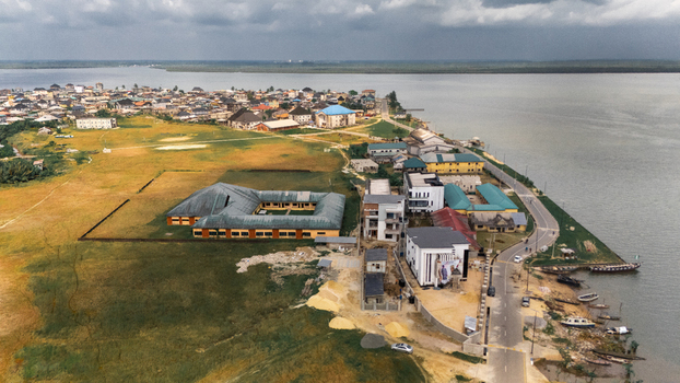 Aerial view of a coastal town with a large courtyard building modern structures and a road running along the riverbank in Minima Rivers Nigeria.