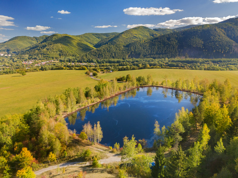 Aerial view of the Gudronove jamy acid tar lagoons surrounded by lush trees and fields with the Low Tatras mountains in the background in Predajna Banskobystricky kraj Slovakia. Aerial view of the Gudronove jamy acid tar lagoons surrounded by lush trees and fields with the Low Tatras mountains in the background in Predajna Banskobystricky kraj Slovakia.