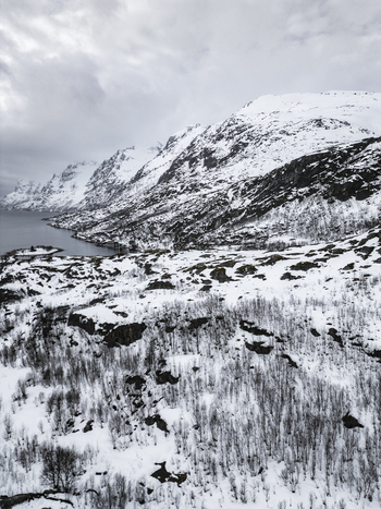 Aerial view of snow covered mountains and a calm fjord under an overcast sky in Ersfjord Troms Norway. Aerial view of snow covered mountains and a calm fjord under an overcast sky in Ersfjord Troms Norway.