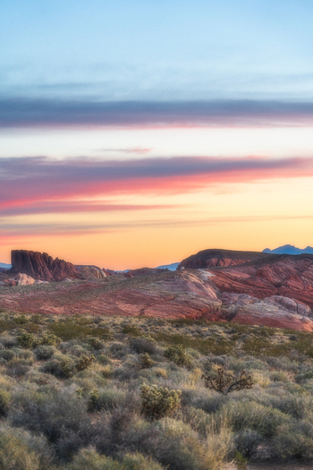 View of Valley of Fire State Park featuring red sandstone formations and desert shrubs under a colorful sunset sky Moapa Valley Nevada United States. View of Valley of Fire State Park featuring red sandstone formations and desert shrubs under a colorful sunset sky Moapa Valley Nevada United States.