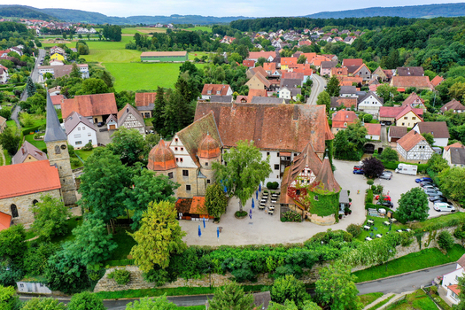 Wiesenthau Germany 02 May 2026 Aerial view of Schloss Wiesenthau with its historic towers and courtyard surrounded by the village houses and green landscape. Wiesenthau Germany 02 May 2026 Aerial view of Schloss Wiesenthau with its historic towers and courtyard surrounded by the village houses and green landscape.