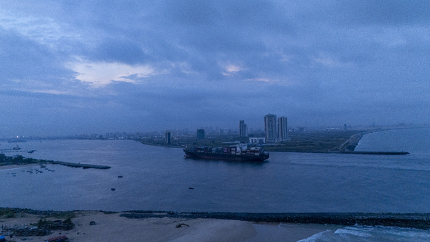 Aerial view of Tarkwa Bay Beach with a large container ship navigating the channel near the Lagos skyline under a cloudy sky in Lagos Lagos Nigeria. Aerial view of Tarkwa Bay Beach with a large container ship navigating the channel near the Lagos skyline under a cloudy sky in Lagos Lagos Nigeria.