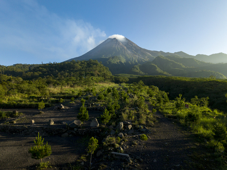 Aerial view of Bunker Kaliadem Merapi with the smoking peak of Mount Merapi volcano and lush green forests in Kecamatan Pakem Daerah Istimewa Yogya Indonesia. Aerial view of Bunker Kaliadem Merapi with the smoking peak of Mount Merapi volcano and lush green forests in Kecamatan Pakem Daerah Istimewa Yogya Indonesia.