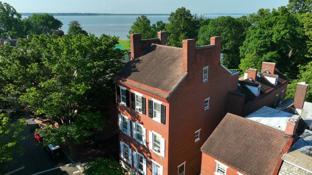 Aerial view of a historic brick building with white shutters surrounded by lush green trees near the Delaware River in New Castle Delaware United States.