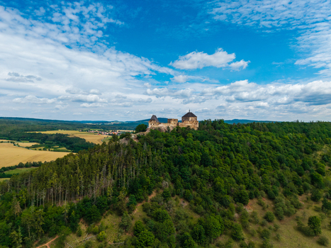 Aerial view of Tocnik Castle situated on a forested hill surrounded by rolling fields and a blue sky with scattered clouds in Tocnik Stredocesky kraj Czechia. Aerial view of Tocnik Castle situated on a forested hill surrounded by rolling fields and a blue sky with scattered clouds in Tocnik Stredocesky kraj Czechia.