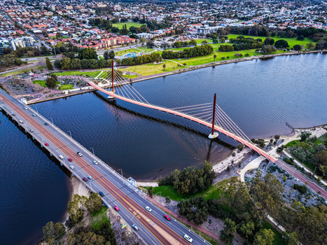 Aerial view of Boorloo Bridge spanning the Swan River with surrounding parklands urban roads and lush greenery in East Perth Western Australia Australia.