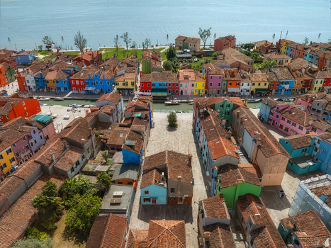 Aerial view of vibrant houses reflecting in the canals of Burano a picturesque island with its kaleidoscope of colors under the clear sky Venice Veneto Italy. Aerial view of vibrant houses reflecting in the canals of Burano a picturesque island with its kaleidoscope of colors under the clear sky Venice Veneto Italy.