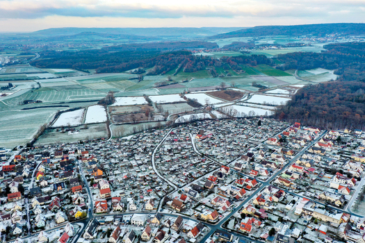 Aerial view of the residential district of Forchheim with snow dusted rooftops surrounding agricultural fields and the Grosser Weiher ponds Forchheim Bayern Germany.