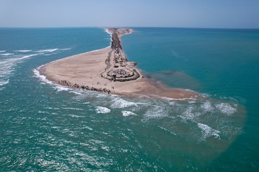 Aerial view of the narrow Dhanushkodi peninsula and Arichal Munai road surrounded by turquoise waters with people on the beach Dhanushkodi Tamil Nadu India.