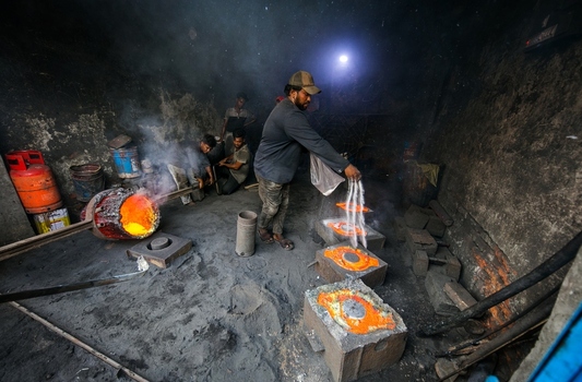 Dhaka Bangladesh 20 April 2026 View of a worker skillfully pouring vivid molten metal into molds casting a brilliant orange glow against the dark smoky foundry interior.