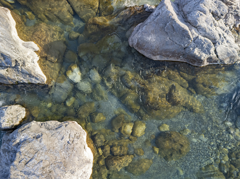 Aerial view of the clear shallow waters of the Kiri River flowing over smooth river stones and large boulders in Shkoder Qarku i Shkodres Albania. Aerial view of the clear shallow waters of the Kiri River flowing over smooth river stones and large boulders in Shkoder Qarku i Shkodres Albania.