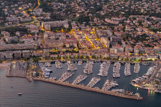 Aerial view of the marina in Antibes with numerous yachts and boats docked in the harbor surrounded by illuminated buildings at dusk in Antibes Provence Alpes Cote d Azur France. Aerial view of the marina in Antibes with numerous yachts and boats docked in the harbor surrounded by illuminated buildings at dusk in Antibes Provence Alpes Cote d Azur France.