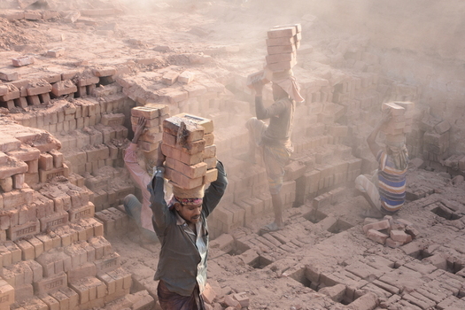 Kushtia District Khulna Division Bangladesh 28 November 2020 View of workers carrying heavy stacks of bricks on their heads in a dusty brick kiln. Kushtia District Khulna Division Bangladesh 28 November 2020 View of workers carrying heavy stacks of bricks on their heads in a dusty brick kiln.