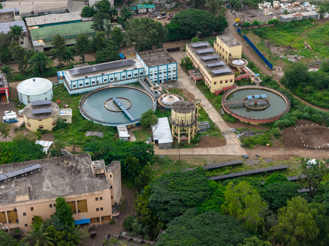 Aerial view of a water treatment plant featuring circular sedimentation tanks and industrial buildings surrounded by lush greenery in Karad Maharashtra India.