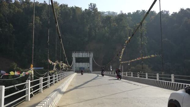 View of a bridge with motorcycles and prayer flags Nepal.
