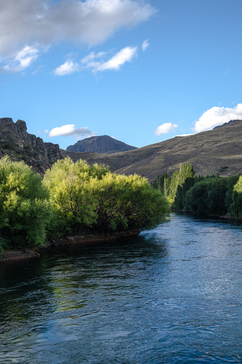 View of the Limay River flowing past the lush green trees and rugged hills of Villa Llanquin in Cipolletti Rio Negro Argentina. View of the Limay River flowing past the lush green trees and rugged hills of Villa Llanquin in Cipolletti Rio Negro Argentina.