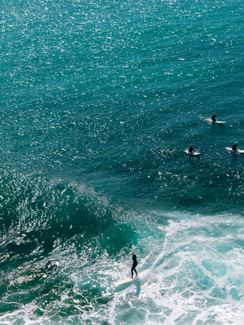 Aerial view of surfers riding waves in the turquoise ocean at Dee Why New South Wales Australia. Aerial view of surfers riding waves in the turquoise ocean at Dee Why New South Wales Australia.