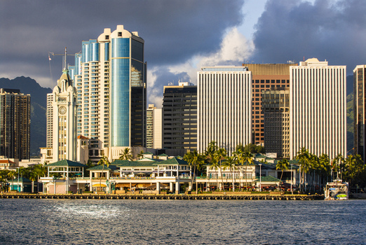 View of the Honolulu skyline featuring the historic Aloha Tower modern skyscrapers and palm trees along the waterfront Honolulu Hawaii United States.