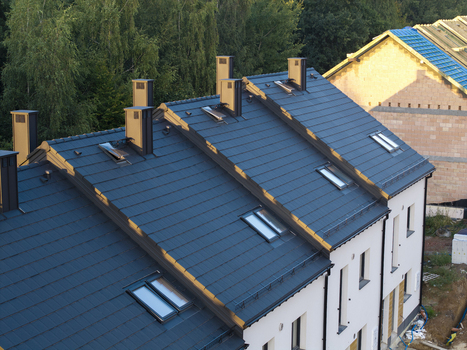 Aerial view of modern residential houses with dark tiled roofs chimneys and skylights in Poland. Aerial view of modern residential houses with dark tiled roofs chimneys and skylights in Poland.