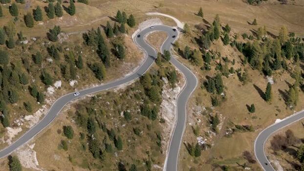 Aerial view of winding road of Gardena Pass with cars Italy.
