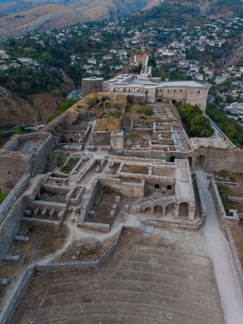 Aerial view of Gjirokaster Fortress featuring ancient stone ruins historic fortifications and surrounding hillside architecture in Gjirokaster Gjirokaster County Albania. Aerial view of Gjirokaster Fortress featuring ancient stone ruins historic fortifications and surrounding hillside architecture in Gjirokaster Gjirokaster County Albania.