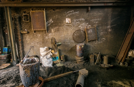 Dhaka Bangladesh 20 April 2026 View of a dark grimy workshop interior showcasing rough textured walls with faded writings and industrial tools.