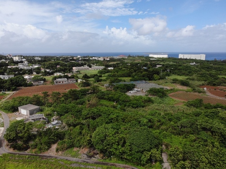 Aerial view of the lush landscape of Sesoko Island featuring dense greenery agricultural fields and distant views of the Motobu Peninsula across the sea in Motobu Okinawa Japan. Aerial view of the lush landscape of Sesoko Island featuring dense greenery agricultural fields and distant views of the Motobu Peninsula across the sea in Motobu Okinawa Japan.