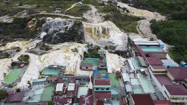 Aerial view of the geothermal hot springs in Sipoholon with white mineral deposits turquoise pools and surrounding buildings in Tarutung North Sumatra Indonesia. Aerial view of the geothermal hot springs in Sipoholon with white mineral deposits turquoise pools and surrounding buildings in Tarutung North Sumatra Indonesia.