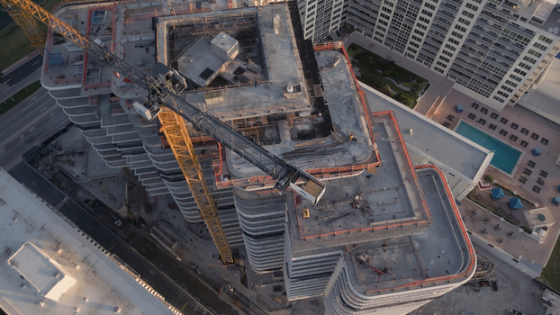 Aerial view of a high rise building under construction featuring a large yellow tower crane concrete floor plates and structural steel framing in Miami Beach Florida United States. Aerial view of a high rise building under construction featuring a large yellow tower crane concrete floor plates and structural steel framing in Miami Beach Florida United States.