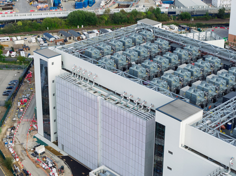 Aerial view of a modern data center facility featuring extensive rooftop cooling units and industrial infrastructure in the United Kingdom. Aerial view of a modern data center facility featuring extensive rooftop cooling units and industrial infrastructure in the United Kingdom.