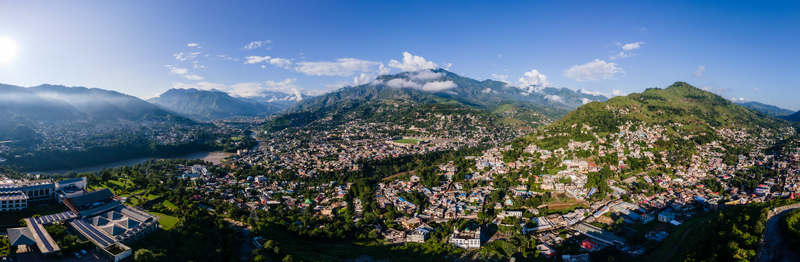 Aerial view of the city of Muzaffarabad nestled in a lush green valley with a winding river and towering mountains under a bright blue sky Muzaffarabad Azad Kashmir Pakistan. Aerial view of the city of Muzaffarabad nestled in a lush green valley with a winding river and towering mountains under a bright blue sky Muzaffarabad Azad Kashmir Pakistan.