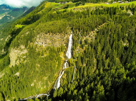Aerial view of Stuibenfall waterfall cascading down a lush pine covered mountain slope with a winding hiking trail and suspension bridge in Niederthai Tirol Austria. Aerial view of Stuibenfall waterfall cascading down a lush pine covered mountain slope with a winding hiking trail and suspension bridge in Niederthai Tirol Austria.