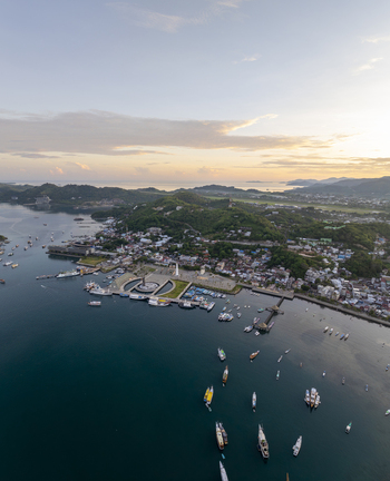 Aerial view of Labuan Bajo harbor with numerous boats anchored in the bay surrounded by lush green hills and the coastal town of Komodo East Nusa Tenggara Indonesia. Aerial view of Labuan Bajo harbor with numerous boats anchored in the bay surrounded by lush green hills and the coastal town of Komodo East Nusa Tenggara Indonesia.