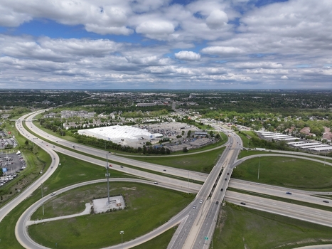 Aerial view of a highway interchange and large commercial building surrounded by green fields and suburban neighborhoods under a cloudy sky in Columbus Ohio United States. Aerial view of a highway interchange and large commercial building surrounded by green fields and suburban neighborhoods under a cloudy sky in Columbus Ohio United States.