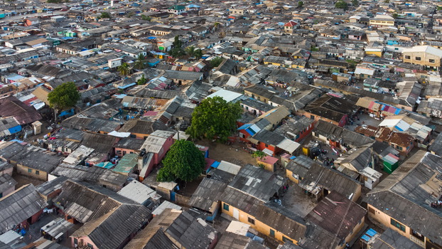 Aerial view of the dense residential neighborhood of Teshie with corrugated metal rooftops narrow alleyways and scattered trees in Accra Greater Accra Region Ghana.