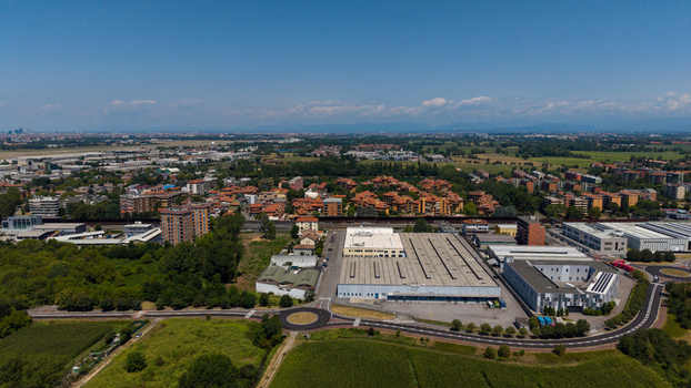 Aerial view of industrial warehouses and surrounding residential buildings with green fields and a roundabout in Milan Lombardy Italy. Aerial view of industrial warehouses and surrounding residential buildings with green fields and a roundabout in Milan Lombardy Italy.
