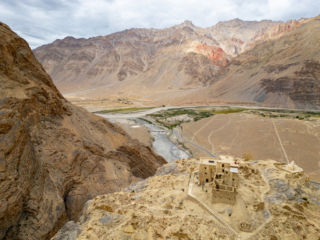 Aerial view of Zanskar monastery perched on a rocky cliff overlooking the winding river and vast arid mountain landscape in Zanskar Ladakh India.