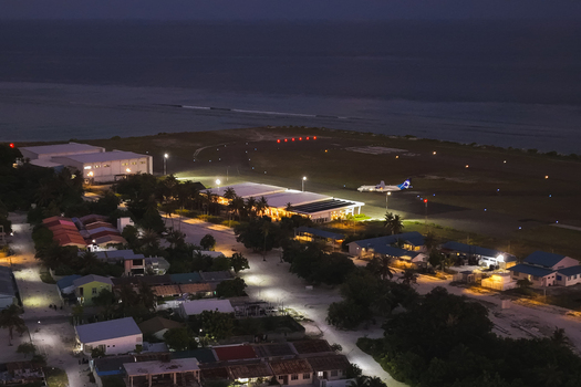 Aerial view of Dhaalu Airport at night with illuminated runway terminal building and a parked aircraft surrounded by the residential area of Kudahuvadhoo Dhaalu Atoll Maldives. Aerial view of Dhaalu Airport at night with illuminated runway terminal building and a parked aircraft surrounded by the residential area of Kudahuvadhoo Dhaalu Atoll Maldives.