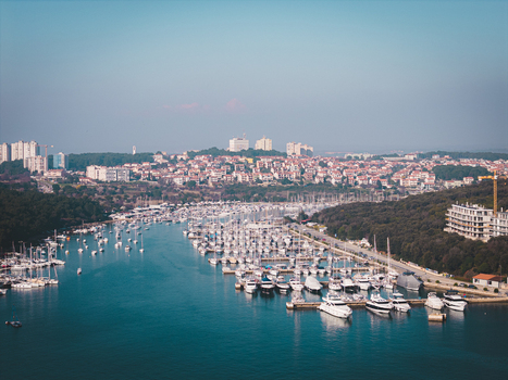 Aerial view of a myriad of white boats dance in the marina s embrace juxtaposed against the red tiled roofs and verdant coastline Pula Istria County Croatia.
