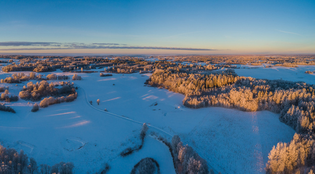 Aerial view of snow covered fields and frost covered trees in the winter landscape of Latvia. Aerial view of snow covered fields and frost covered trees in the winter landscape of Latvia.