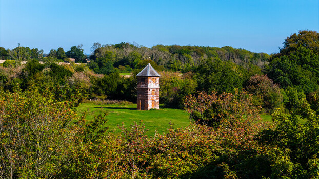 Aerial view of the historic Pepperbox Hill Folly surrounded by lush green trees and fields in Salisbury England United Kingdom. Aerial view of the historic Pepperbox Hill Folly surrounded by lush green trees and fields in Salisbury England United Kingdom.