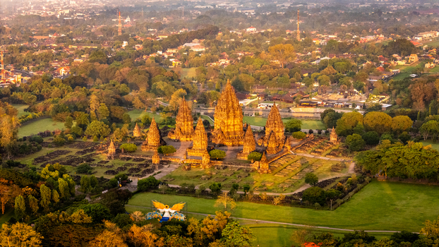 Aerial view of the ancient Prambanan Temple complex with its towering stone spires surrounded by lush green lawns and trees at sunset in Kecamatan Prambanan Daerah Istimewa Yogya Indonesia. Aerial view of the ancient Prambanan Temple complex with its towering stone spires surrounded by lush green lawns and trees at sunset in Kecamatan Prambanan Daerah Istimewa Yogya Indonesia.