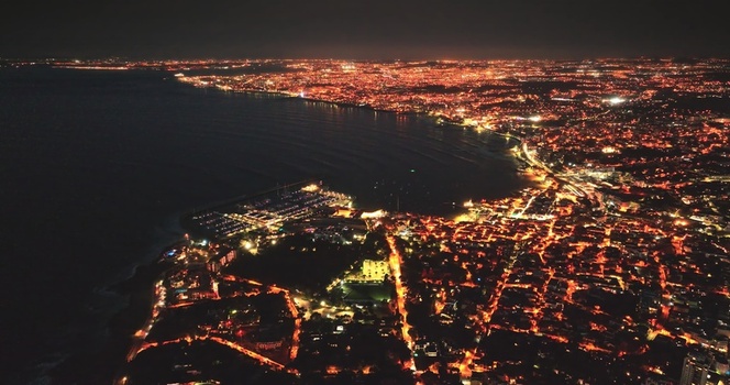 Aerial view of the illuminated cityscape of Lisbon at night featuring the coastline harbor and dense urban street lights along the Tagus River in Lisbon Lisbon Portugal. Aerial view of the illuminated cityscape of Lisbon at night featuring the coastline harbor and dense urban street lights along the Tagus River in Lisbon Lisbon Portugal.